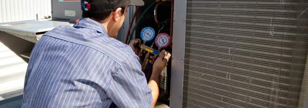 HVAC technician servicing a condenser unit in Lenoir