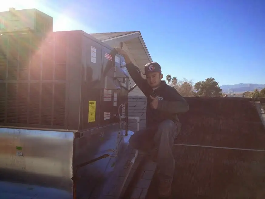 HVAC technician performing AC Tune-Up on a rooftop unit in Lenoir
